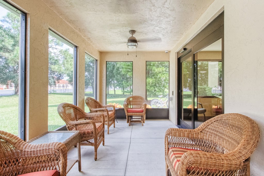 screened in patio with ceiling fan and tables and couches
