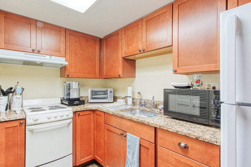 kitchen with ample wood cabinetry, granite countertops, and white appliances
