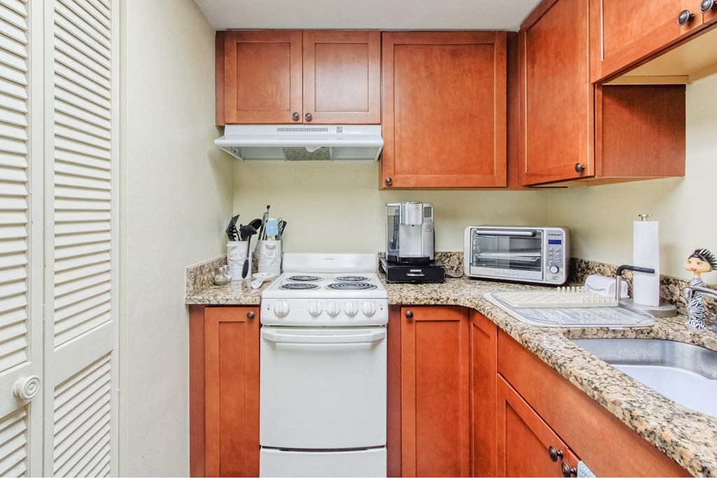 kitchen with pantry, appliances, stainless steel sink, and granite countertops