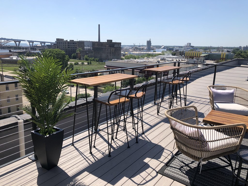 a roof deck with tables and chairs and a city in the background