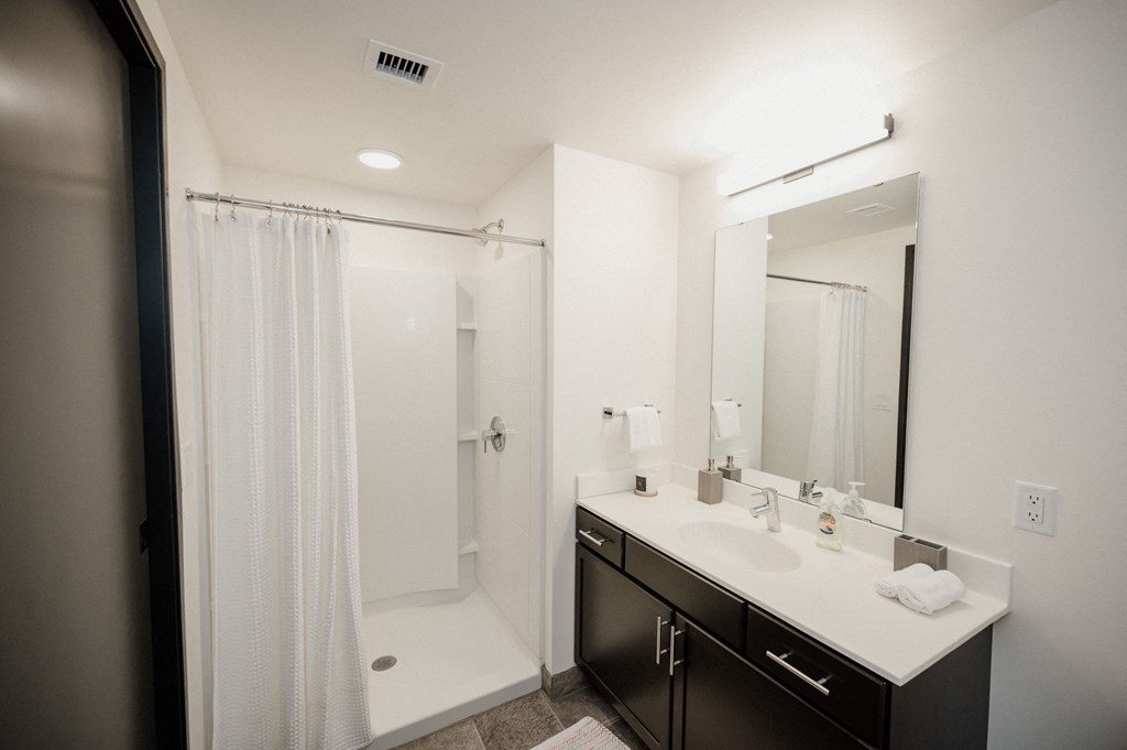 a bathroom with a shower and a sink and a mirror