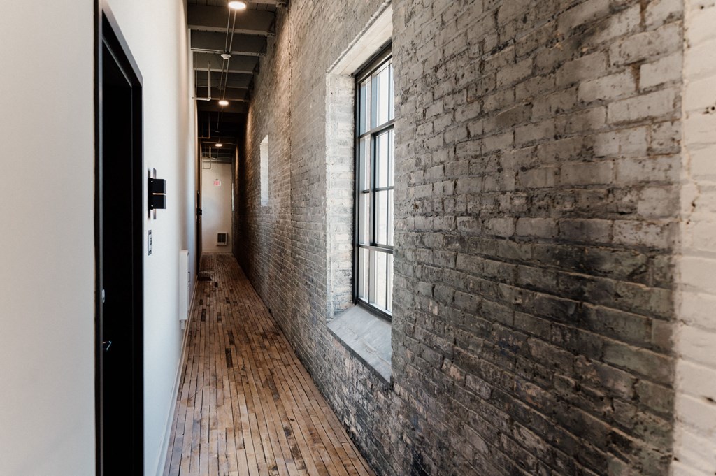 an exposed brick wall in a hallway of a building with a window