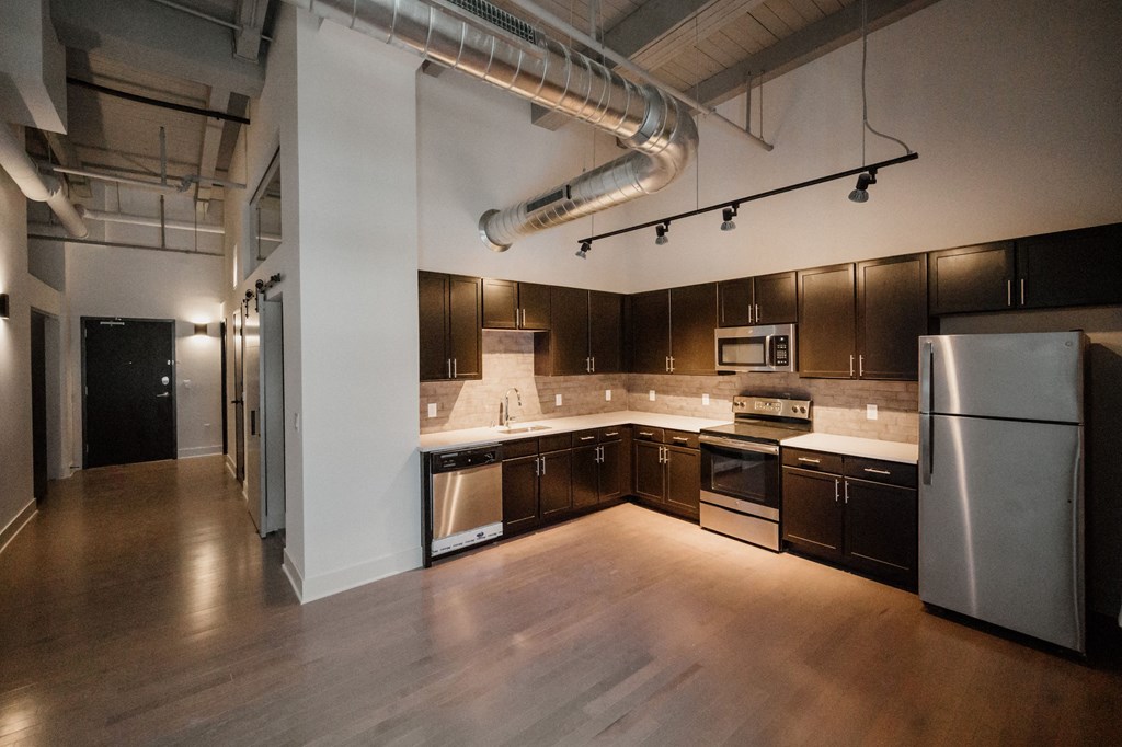 an empty kitchen with wooden floors and stainless steel appliances