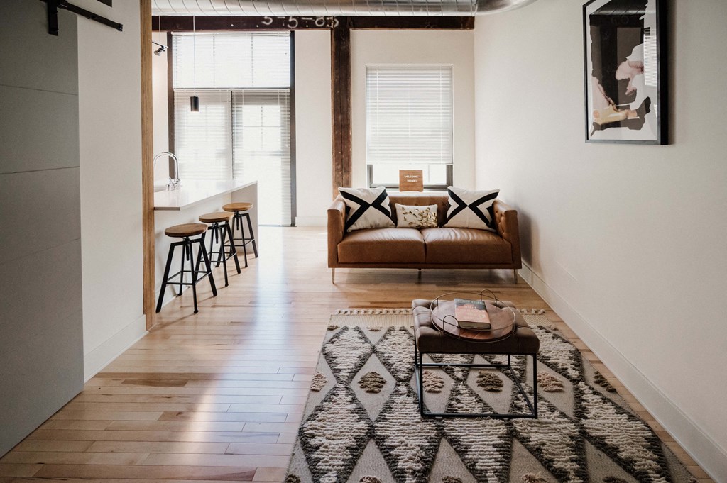 a living room with a couch and a rug and a kitchen