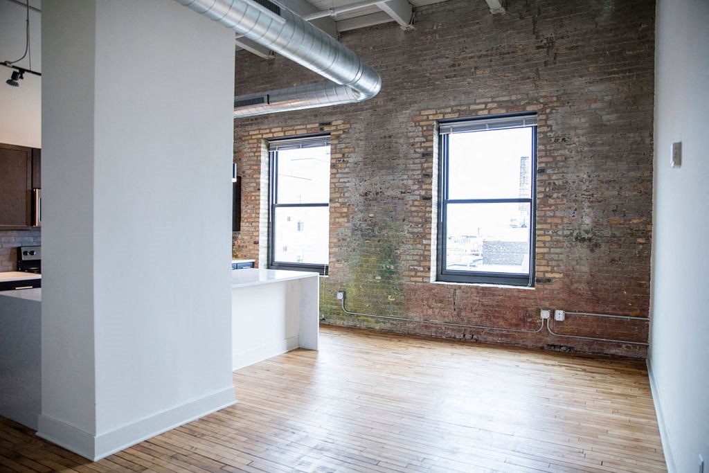 an empty room with an exposed brick wall and wooden floors