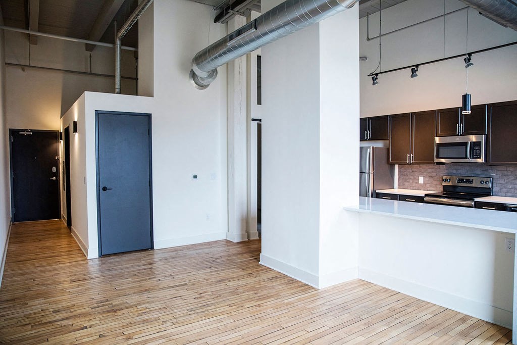 an empty room with a kitchen and a blue door