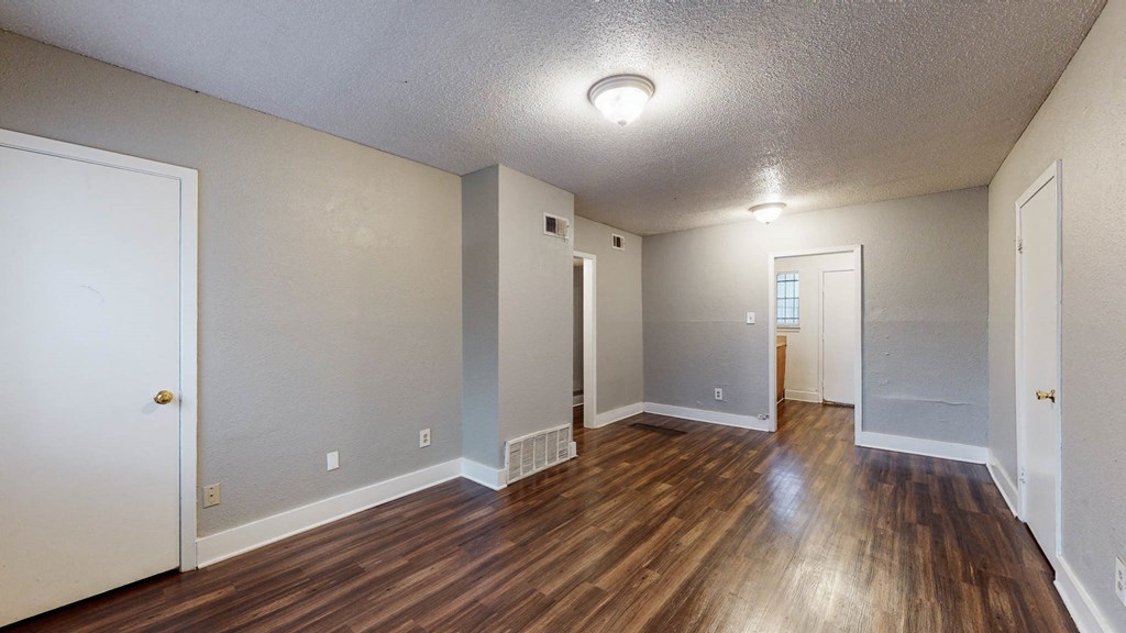 the living room and dining room of an empty house with wood flooring