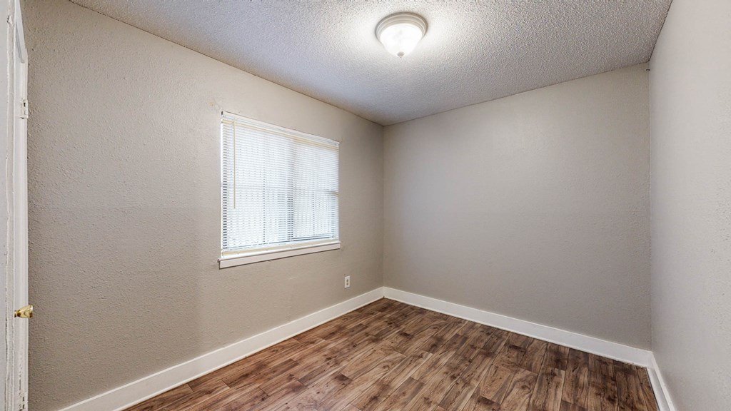the bedroom of our studio apartment has a hardwood floor and a window
