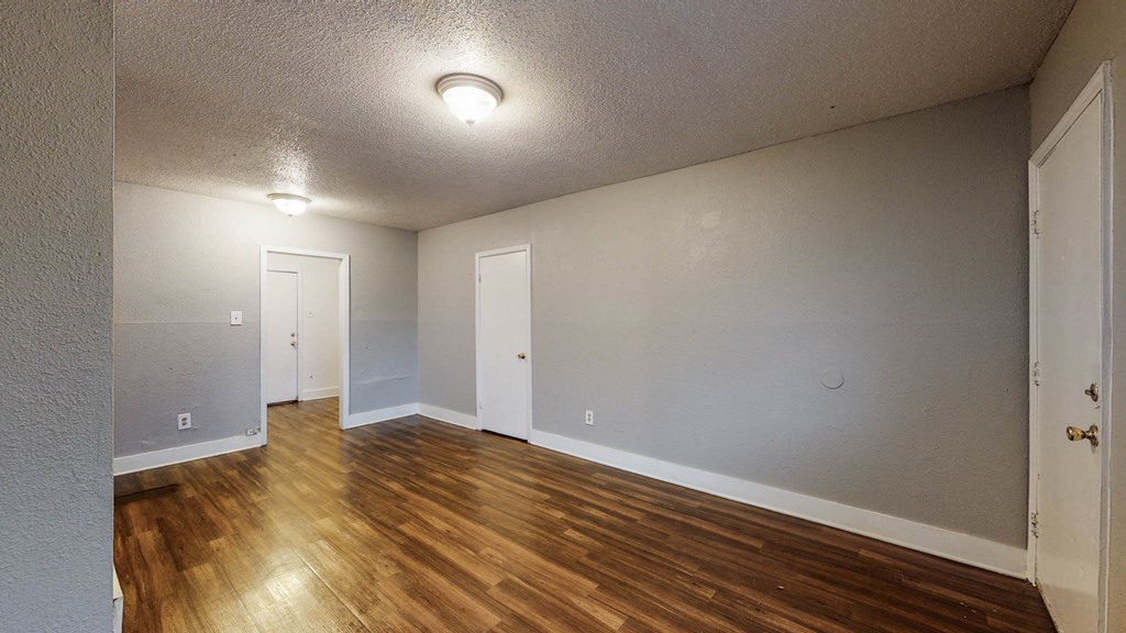 an empty living room with wood floors and white walls