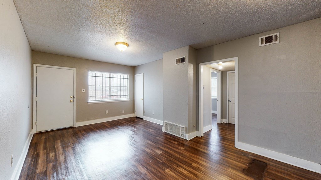 an empty living room with hard wood floors and a window