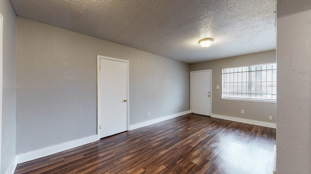 an empty living room with wood flooring and a window