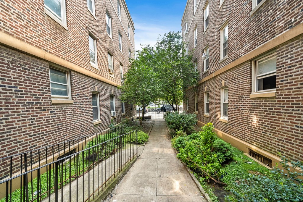an alleyway between two brick buildings with a sidewalk and trees