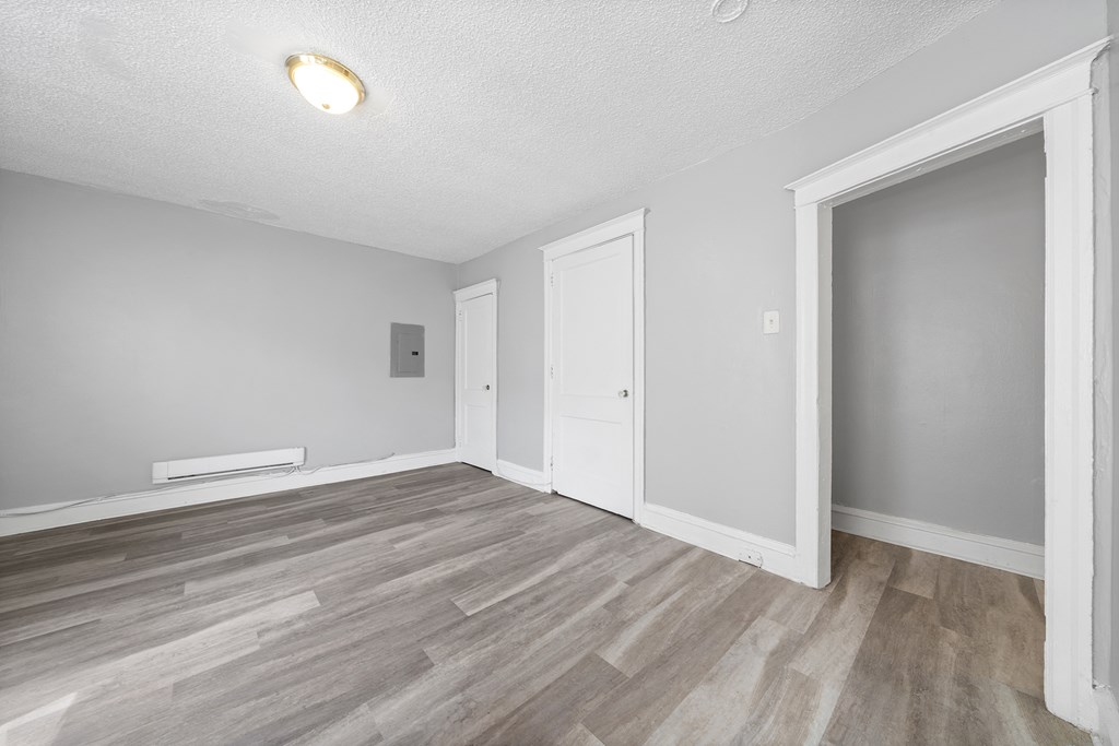 the living room of an empty apartment with wood flooring and white walls and doors