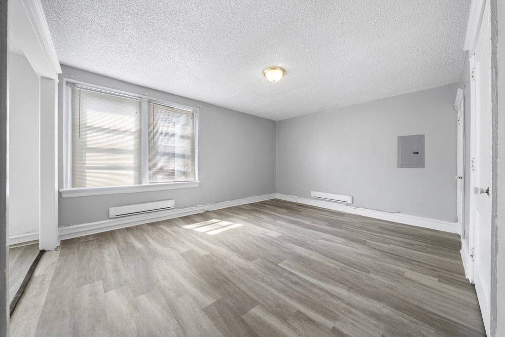 the living room of an empty house with wood flooring and two windows