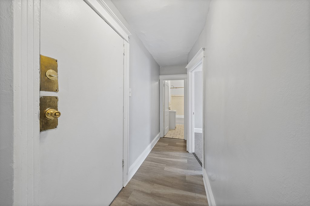a hallway with white walls and a door with a yellow handle