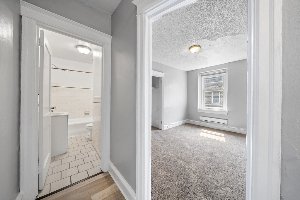 an empty bedroom and bathroom with a view of the bathroom and the living room