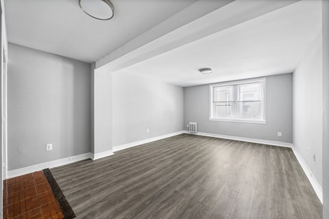 A spacious room with wooden flooring and a window.