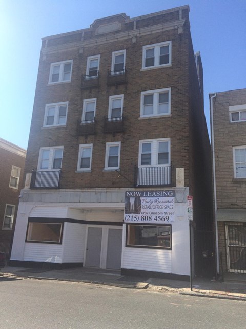 A building with a sign that says "Now Leasing" is in front of another building.