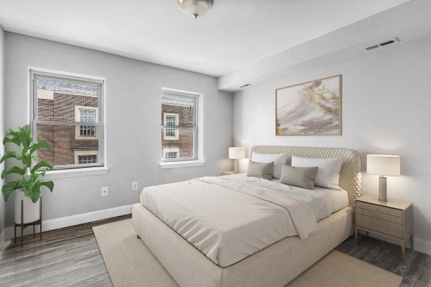 the master bedroom has a large bed and two windows