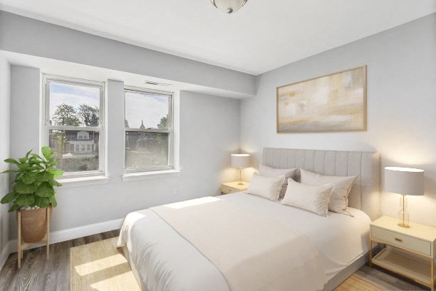 the master bedroom has a large white bed and three windows