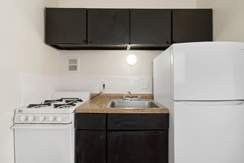 a kitchen with white appliances and black cabinets and a white refrigerator