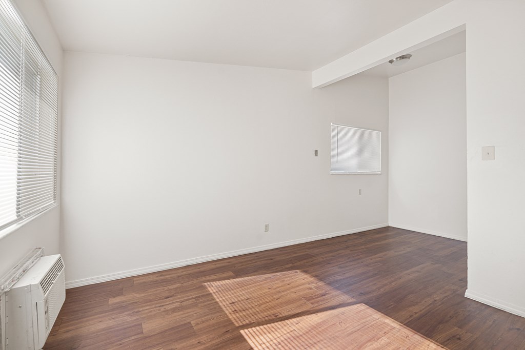 a living room with white walls and wood flooring and a window