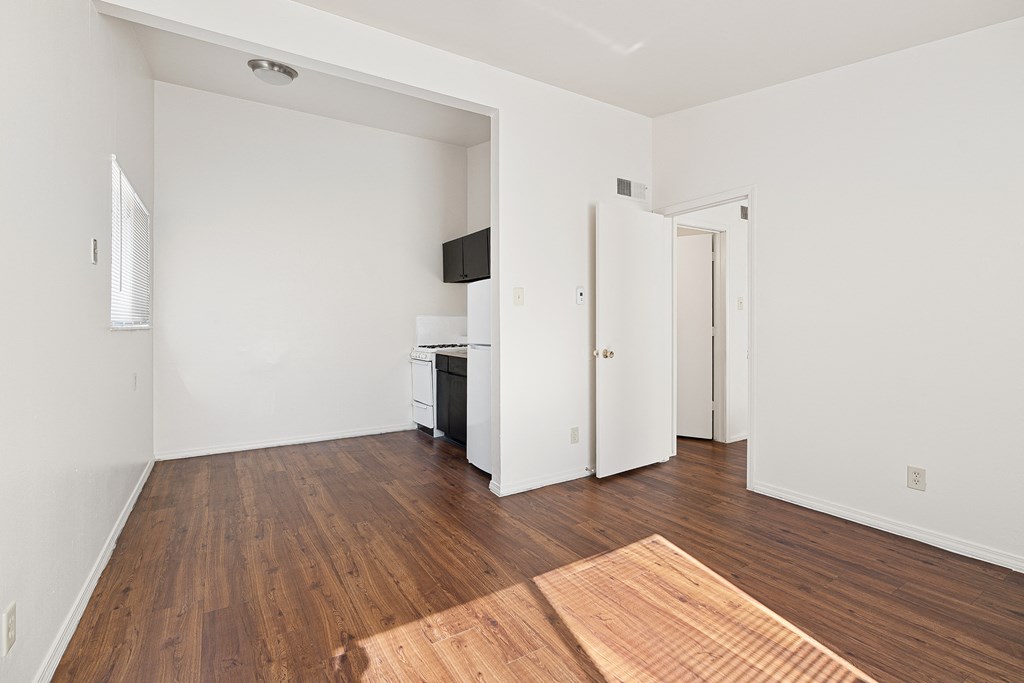an empty living room with wood flooring and white walls