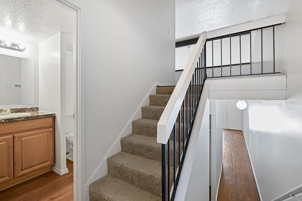 a stairway in a home with a kitchen and a railing on the stairs