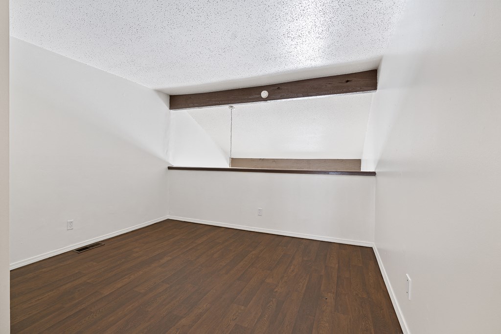 an empty room with wood flooring and white walls