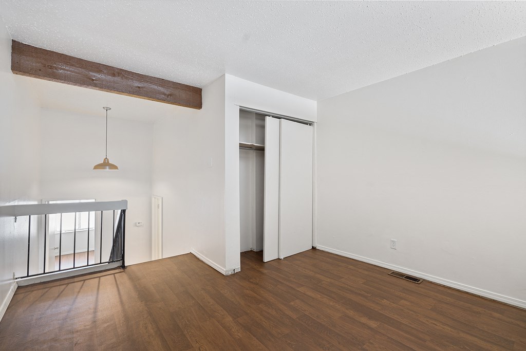 an empty living room with wood flooring and a staircase