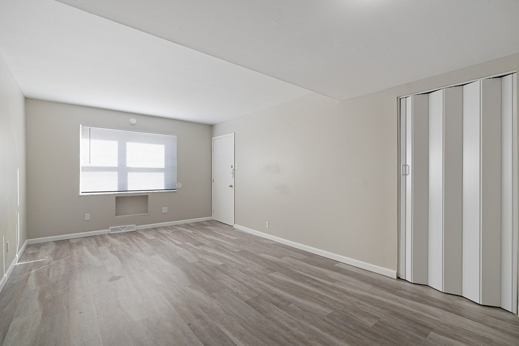 an empty living room with wood floors and a window