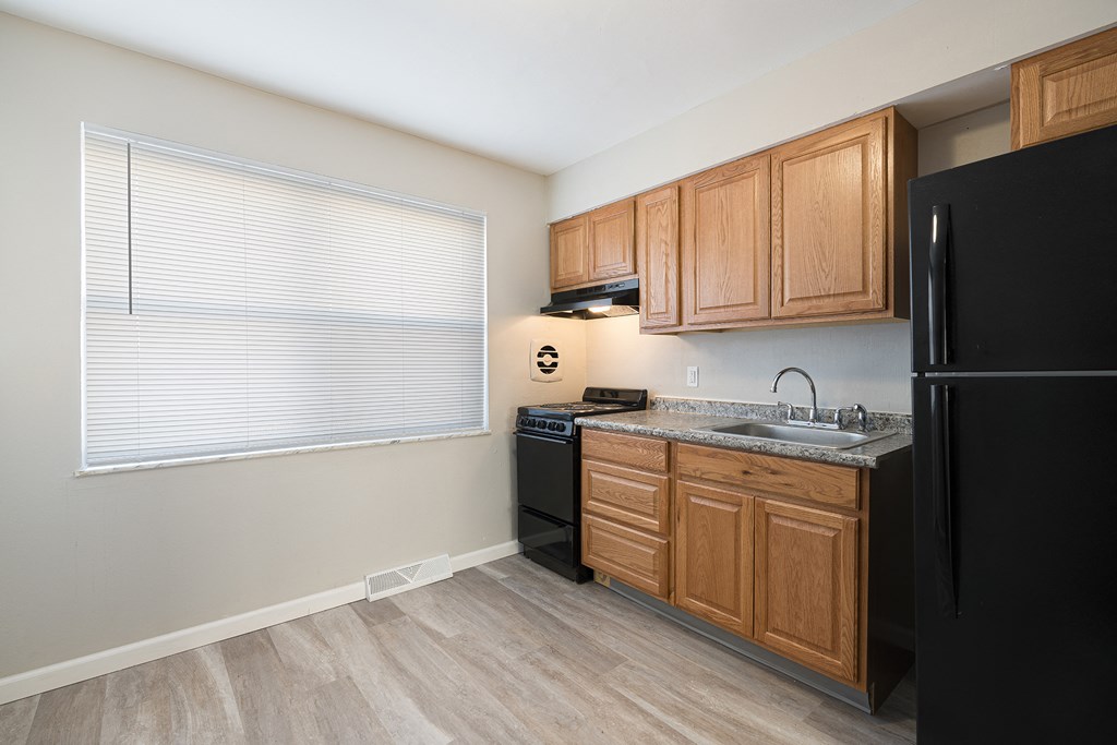 a kitchen with black appliances and wooden cabinets and a window