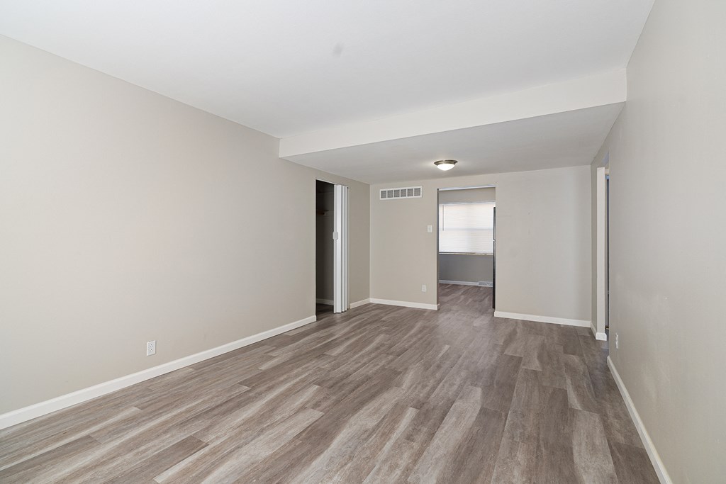 the living room and dining room of an apartment with wood flooring