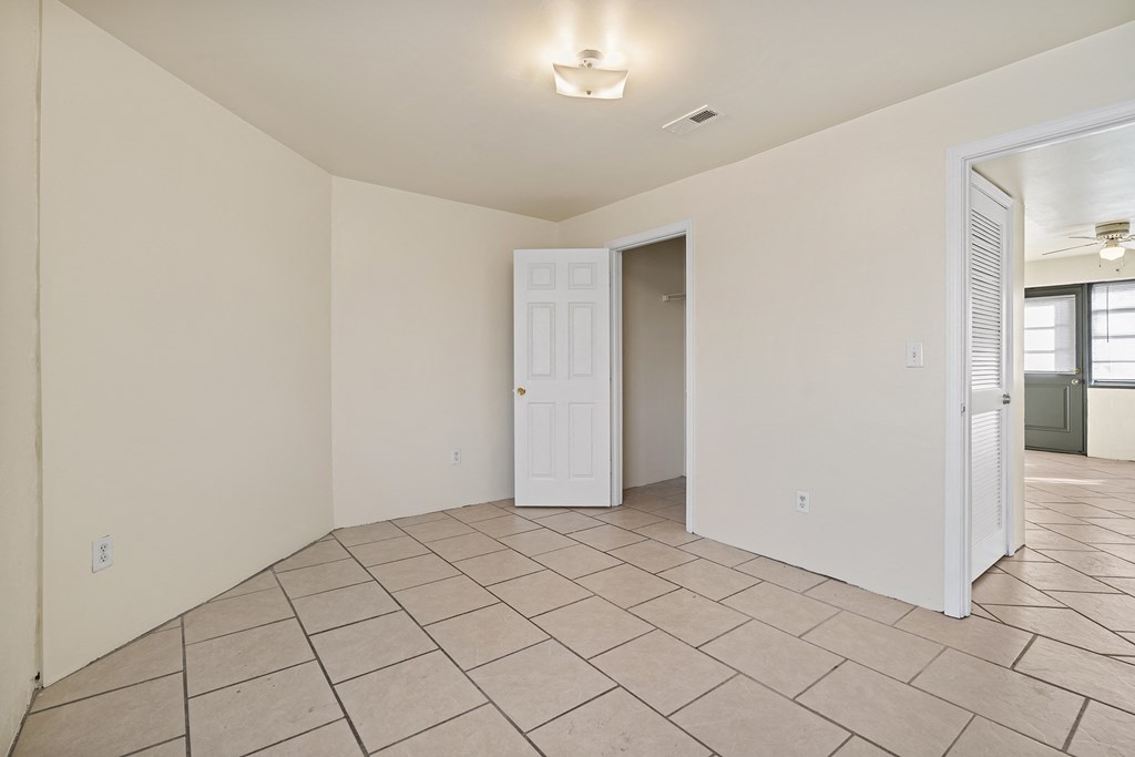 the living room and dining room of a house with tile flooring and a door