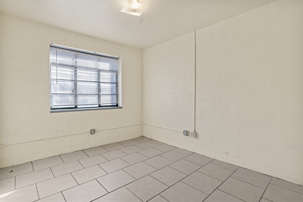 the living room of an empty apartment with a window and tiled floor