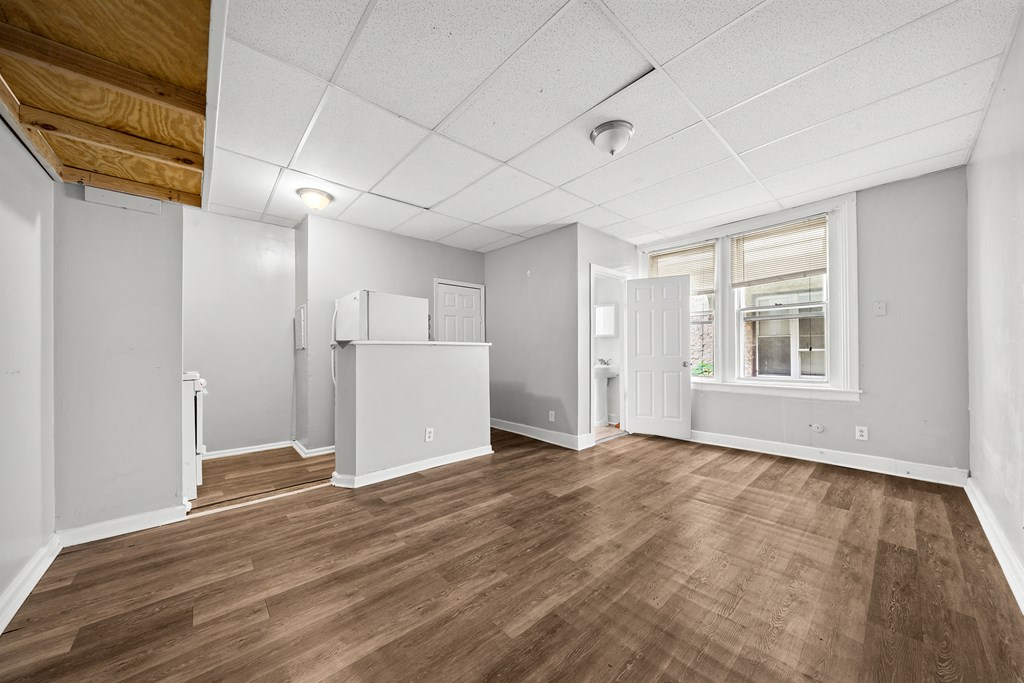 an empty living room with wood floors and a window