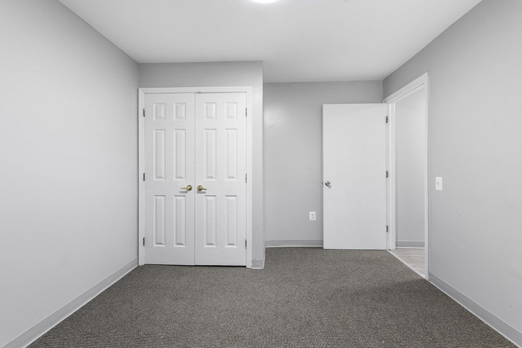 an empty room with white doors and a carpet