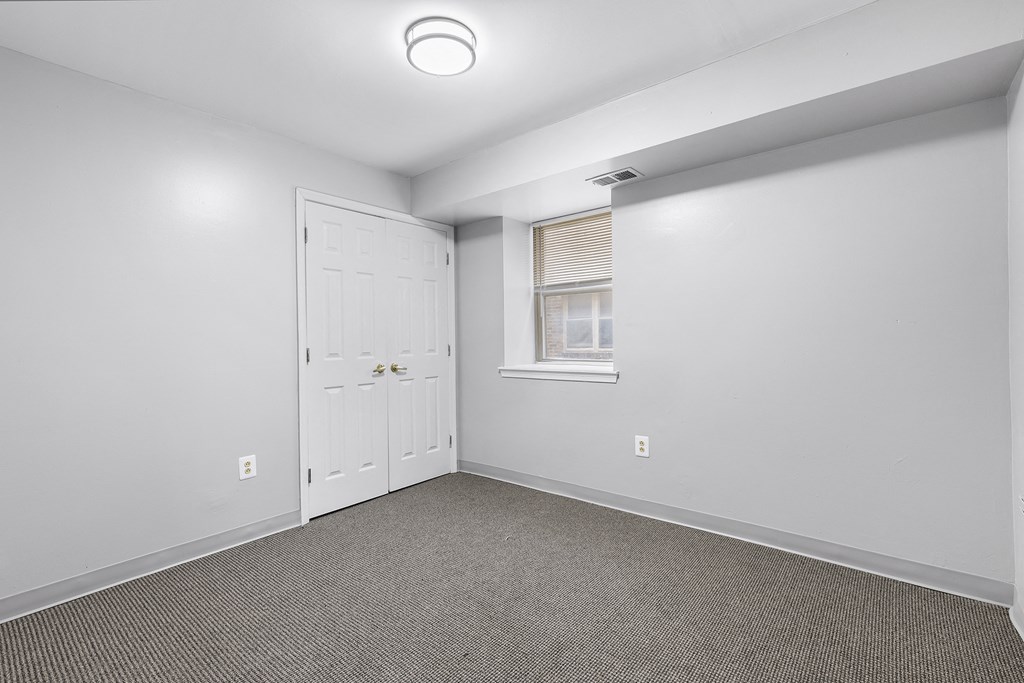 an empty room with carpet and a door to a closet