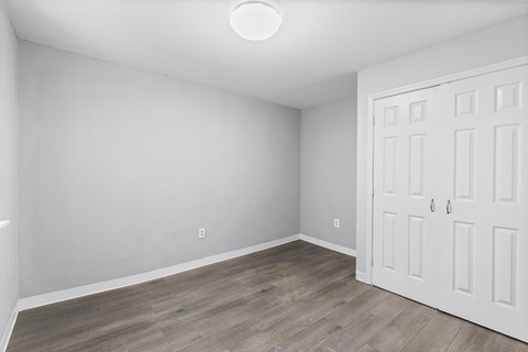 a bedroom with white walls and wood flooring and a white door