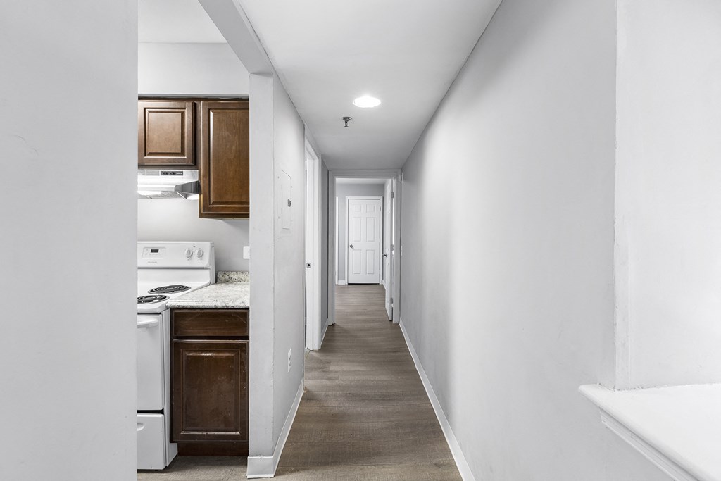 an empty kitchen and hallway with white walls and wood floors