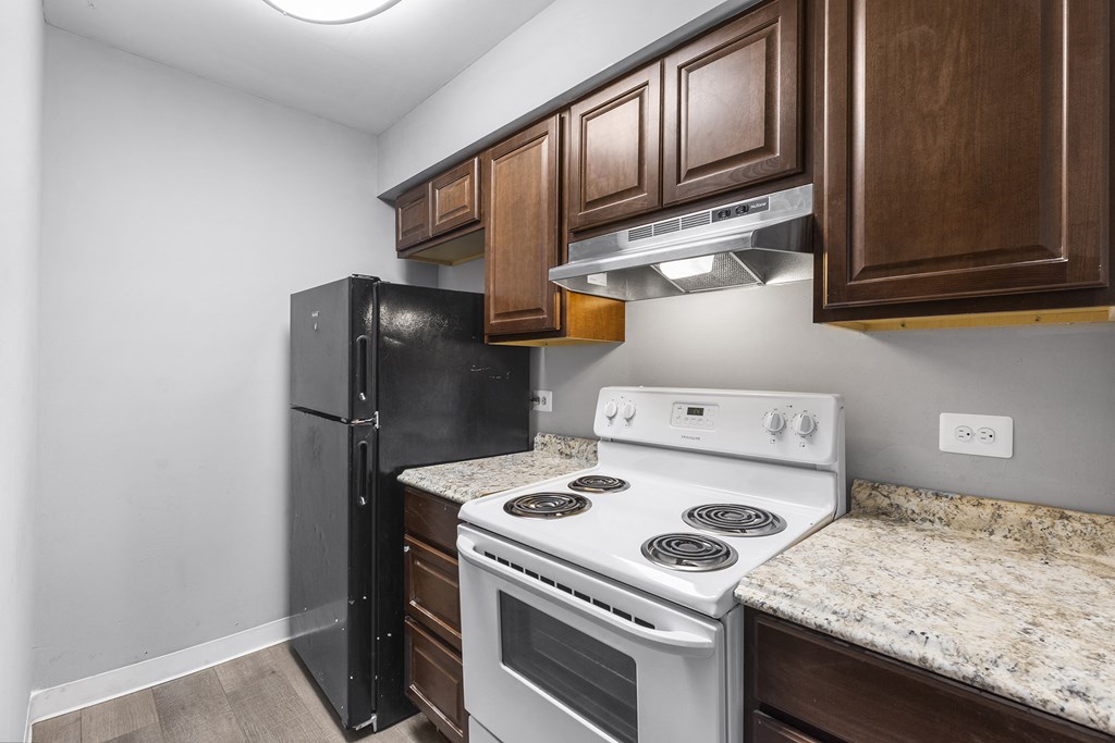 a kitchen with white appliances and wood cabinets and a black refrigerator