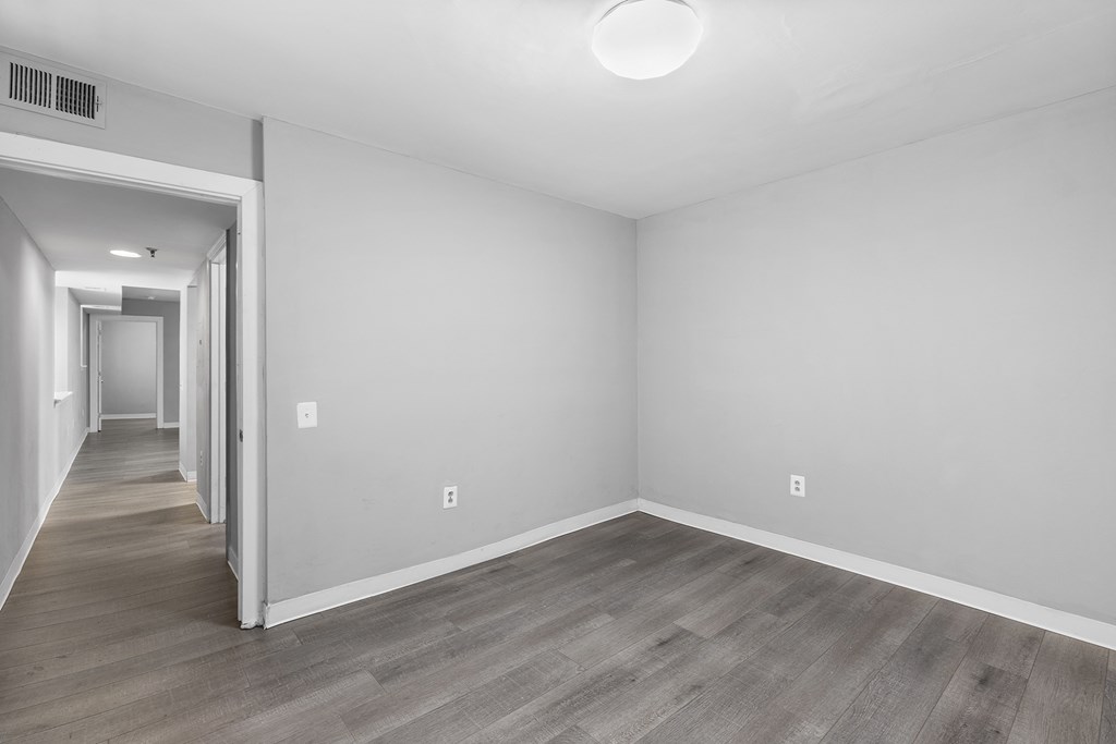 the living room and hallway of an apartment with white walls and wood floors