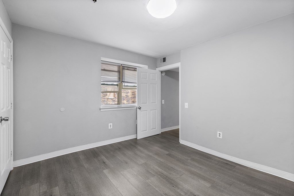 an empty room with white walls and wood floors and a window