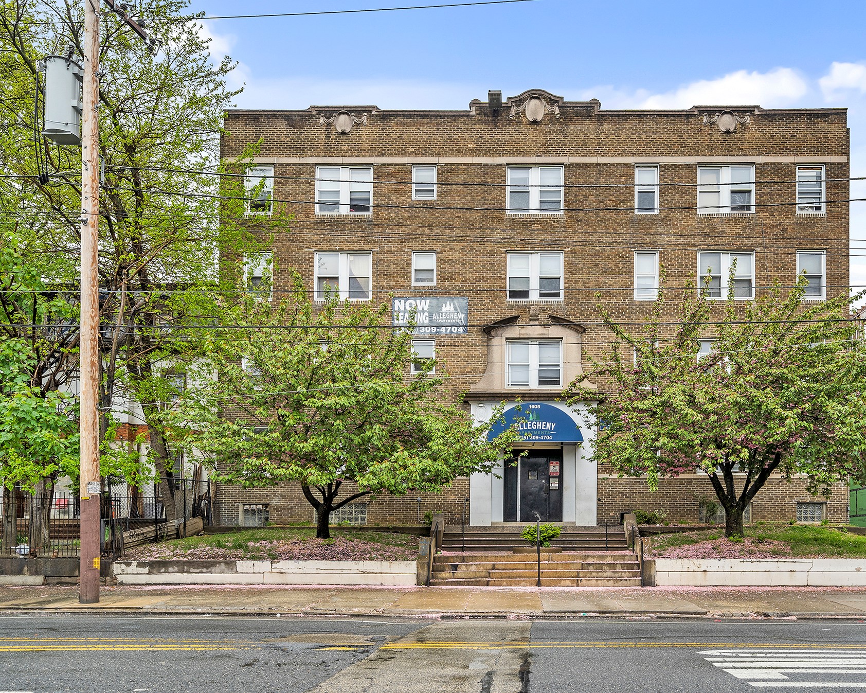 a brick building with trees in front of it on a street