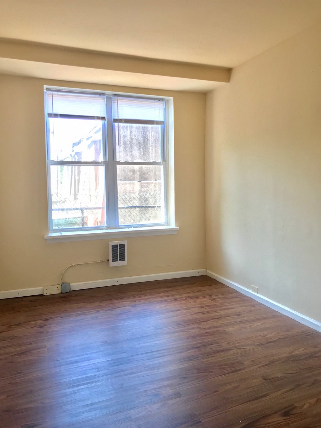 an empty room with a window and wooden floors