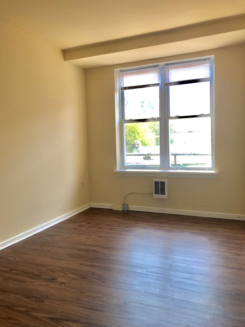 an empty room with a window and wooden floors