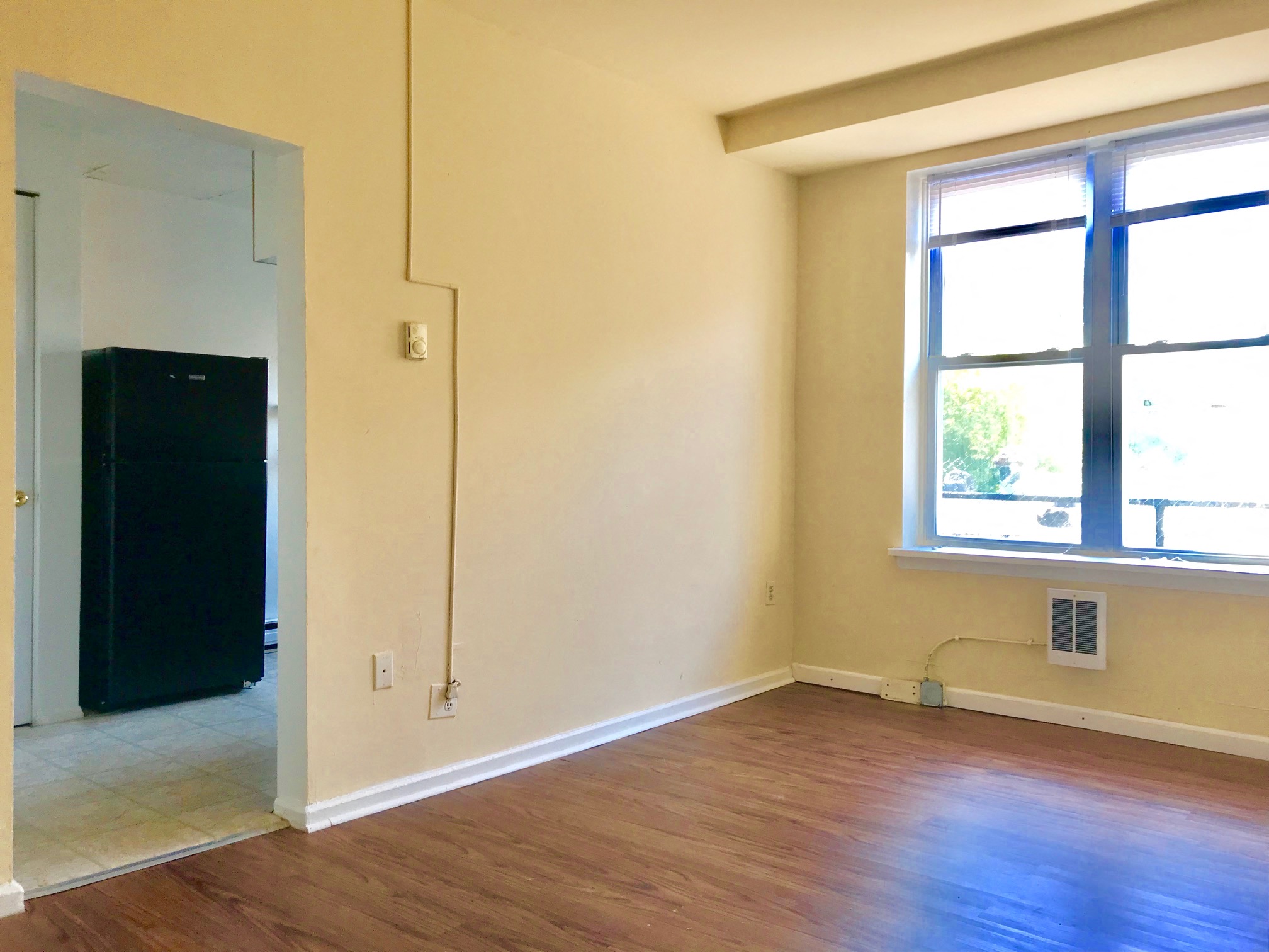 an empty room with a hard wood floor and a window