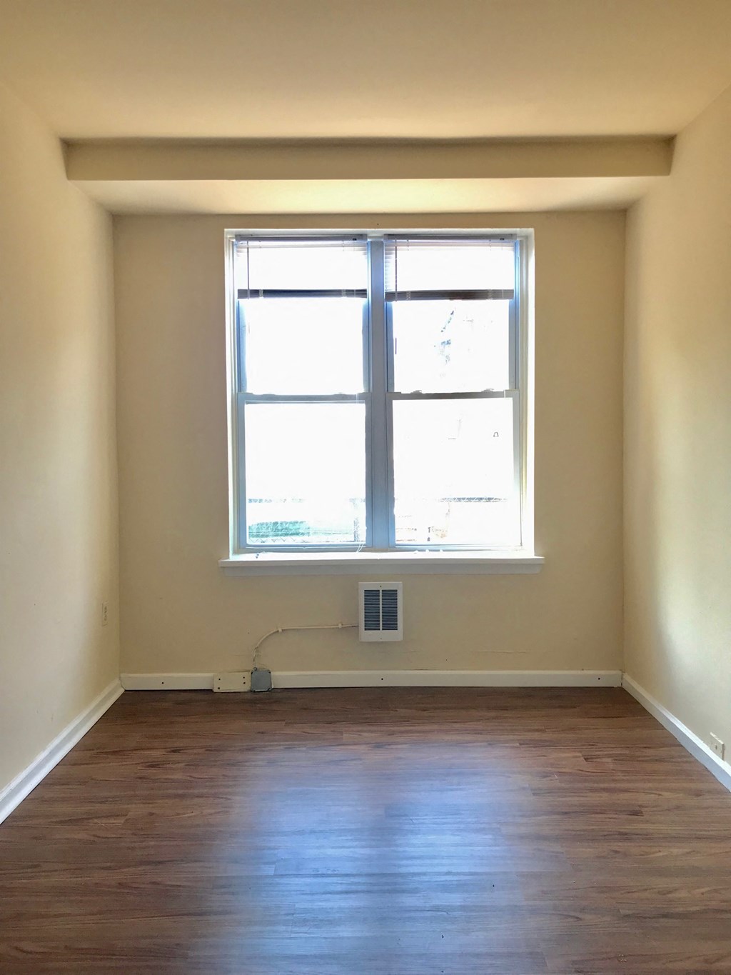 an empty room with a window and wooden floors