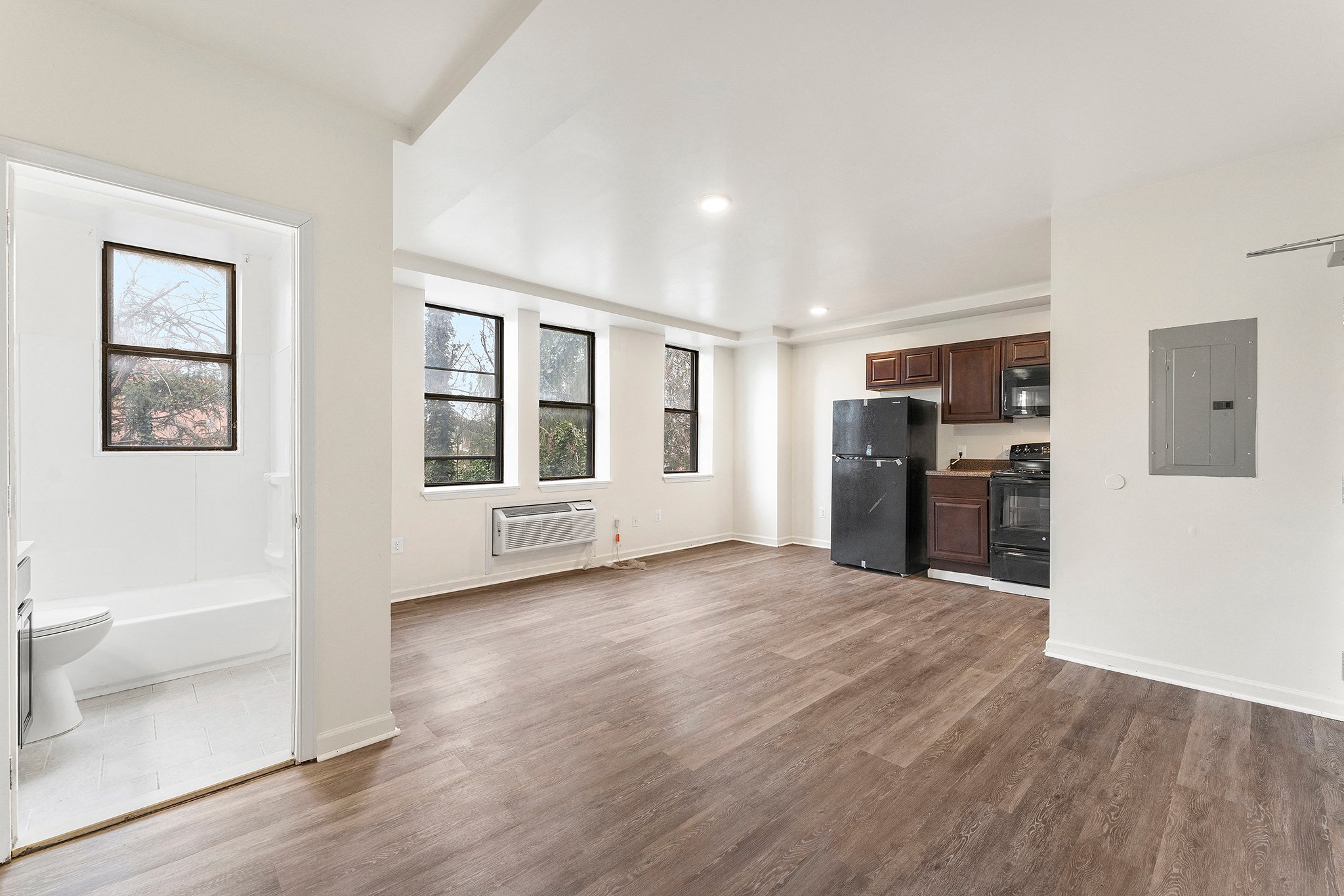 A spacious room with wood flooring and white walls.