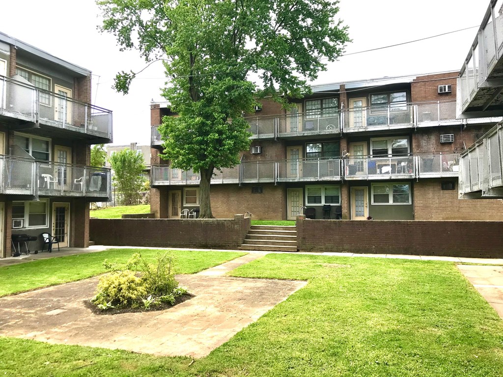 the courtyard of an apartment building with grass and a tree